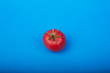 one ripe tomato on a blue background