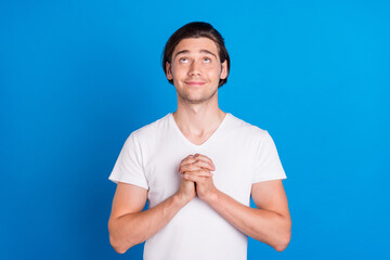 Photo of young happy positive peaceful man look empty space pray please beg isolated on blue color...