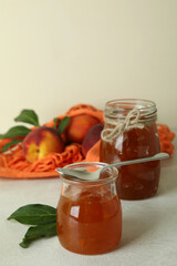 Peach jam and ingredients on white textured table