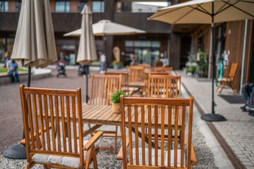 Wooden chairs with a green flowers in the middle of the table of an outdoor restarurant