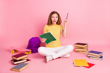 Photo of excited genius girl sit floor write homework have idea wear striped yellow t-shirt...