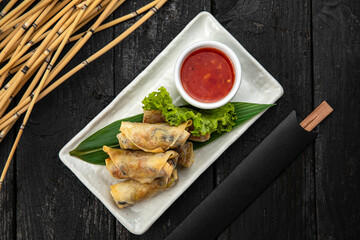Vietnamese rolls with vegetables, rice noodles and prawns with sweet chili sauce on wooden surface
