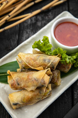 Vietnamese rolls with vegetables, rice noodles and prawns with sweet chili sauce on wooden surface