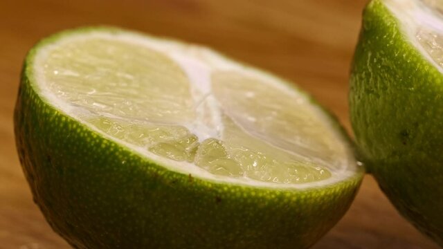 Close-up of a rotating lime. Lime, sliced in half, rotates on a wooden surface