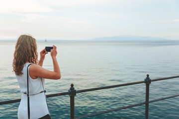 woman taking picture of the sea on the phone