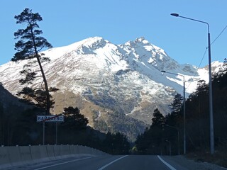 Fototapeta premium View on the road to the Mountains in summer with snow, blue sky on a clear day. 