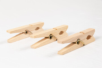three wooden clothespins with a metal spring on the background of a white wooden table. close-up. selective focus