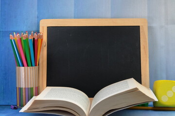 A black board with copy space and school supplies and a book.