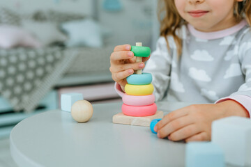 Close up of little toddler girl wearing pajamas playing with wooden toy pyramid