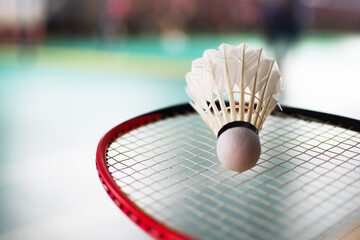 White shuttlecock on badminton racket, blurred badminton court background, concept for badminton lovers around the world.
