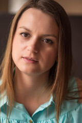 Portrait of a young beautiful brown-haired woman with long hair indoors on a dark background.