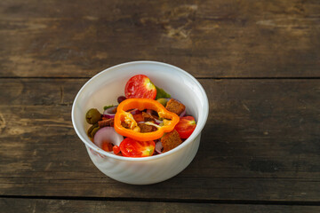 Fresh vegetable salad in a salad bowl on a wooden table.