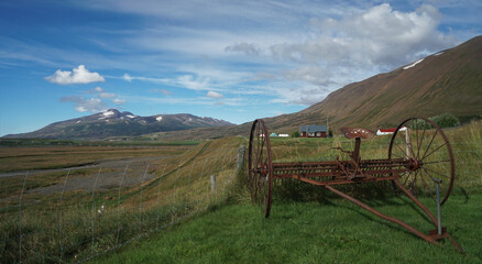 old traditional rusty carriage in the field, under the cloudy sky, Laufas old farmhouse, Akureyri, Iceland