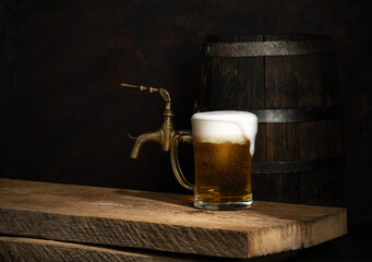 Beer barrel with beer glasses on a wooden table. Dark amber background.