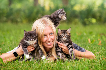 Adorable blonde girl playing with little kittens on warm and sunny summer day