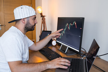 A new generation of young people follow the stock market from home. Young man investing in cryptocurrency exchanges from his home.