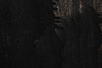 The metal texture of the background painted in black paint with smudges, scratches and splashes of gold sparkles