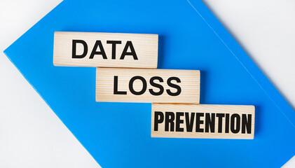 There is a blue notebook on a light gray background. Above are three wooden blocks with the words DATA LOSS PREVENTION.
