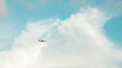 An Airplane flying high in blue sky across the cottony cloud.