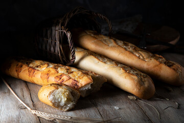 Homemade garlic baguettes and wicker basket on rustic table