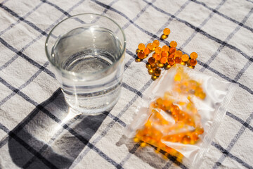 Fish oil capsules on textile background and texture, vitamin D supplement, selective focus