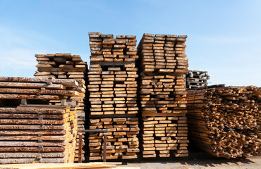 Lumber shop and warehouse. Stacks of pine planks outdoors against blue sky