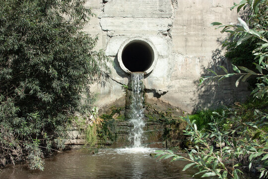 Sewage or sewage water flows out of the drain pipe into the river