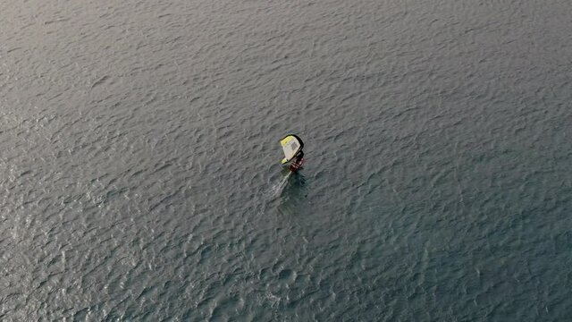 drone shot of man doing windsurfing in the sea.