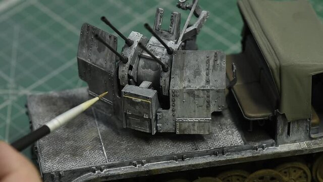 Scale Modeling. Weathering on 1:35 Model of 20mm flakvierling on a prefab plastic model of German 8ton Semi Track. Close up. Plastic Modeling and model building. Hobby and leisure at home. 
