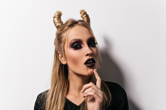 Close-up shot of beautiful vampire. Indoor photo of lady with scary makeup posing in halloween.