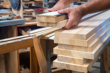 Woodworker stacks boards ready to be planned
