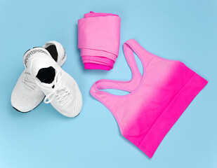 Sports equipment white sneakers and pink clothes on a blue background in the room.