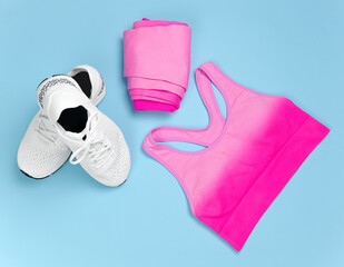 Sports equipment white sneakers and pink clothes on a blue background in the room.