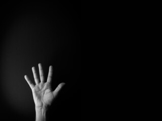 Black and white image of hand demonstrating sign language number five against black background with empty copy space