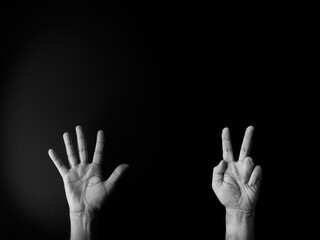 Black and white image of hand demonstrating sign language number seven against black background with empty copy space