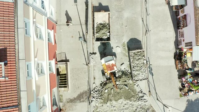 Drone shot from top view on a small excavator digging stone paving stones in the old town of Gdansk, Poland. Repair of paving stones on the street of the old town.