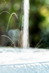 Fonte de água com fundo desfocado e verde.