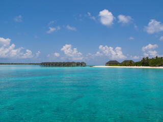Water bungalows on the coast of a white beach and blue ocean in the Maldives. Copy space for text.
