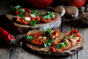 Dried tomatoes bread with oil, garlic and parsley, autumn traditional italian food - bruschetta or antipasti, closeup, healthy vegan food and simple living, rustic aesthetics concept