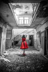Fototapeta na wymiar Frau von hinten in einem verfallenen Haus mit roten Kleid als Color Key Lostplace