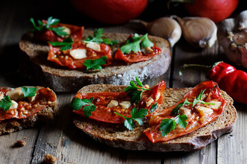 Dried tomatoes bread with oil, garlic and parsley, autumn traditional italian food - bruschetta or antipasti, closeup, healthy vegan food and simple living, rustic aesthetics concept