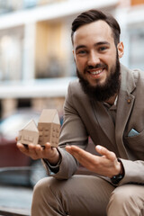 Obraz premium Happy property owner. A man with a miniature house in his hands. Service for renting an apartment, buying an apartment.