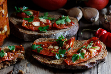 Dried tomatoes bread with oil, garlic and parsley, autumn traditional italian food - bruschetta or antipasti, closeup, healthy vegan food and simple living, rustic aesthetics concept