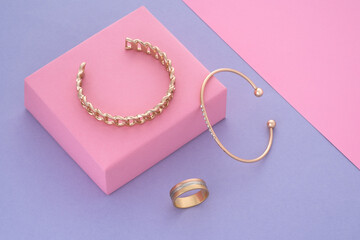 Top view of gold bracelets and ring on pastel colors background copy space