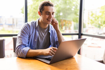 Handsome young freelancer is having a coffee break and dreaming after working with a laptop at coffee shop