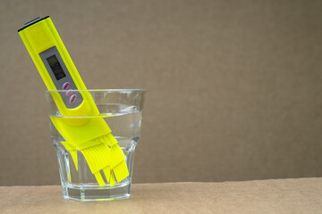 The drinking water quality tester is lowered into a glass of tap water. Checking the purity of water at home.