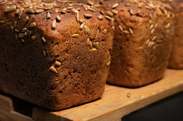 fresh brown loaves of rye bread in the form of bricks with sunflower seeds on a crust. Lie on a wooden rack