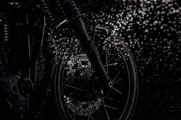 Obraz na płótnie Canvas Motorcycle at wash after off-road driving. Washing front wheel with disc brakes with water. Classic black motorbike. Caferacers style. Maintenance of motor vehicles