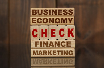 Wooden blocks with the text - Business, Economy, Finance, Marketing and CHECK