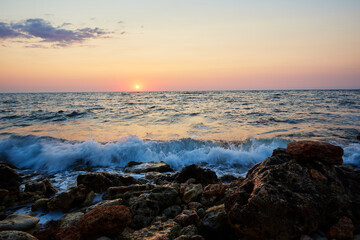 sunset on the rocky coast of the black sea with waves